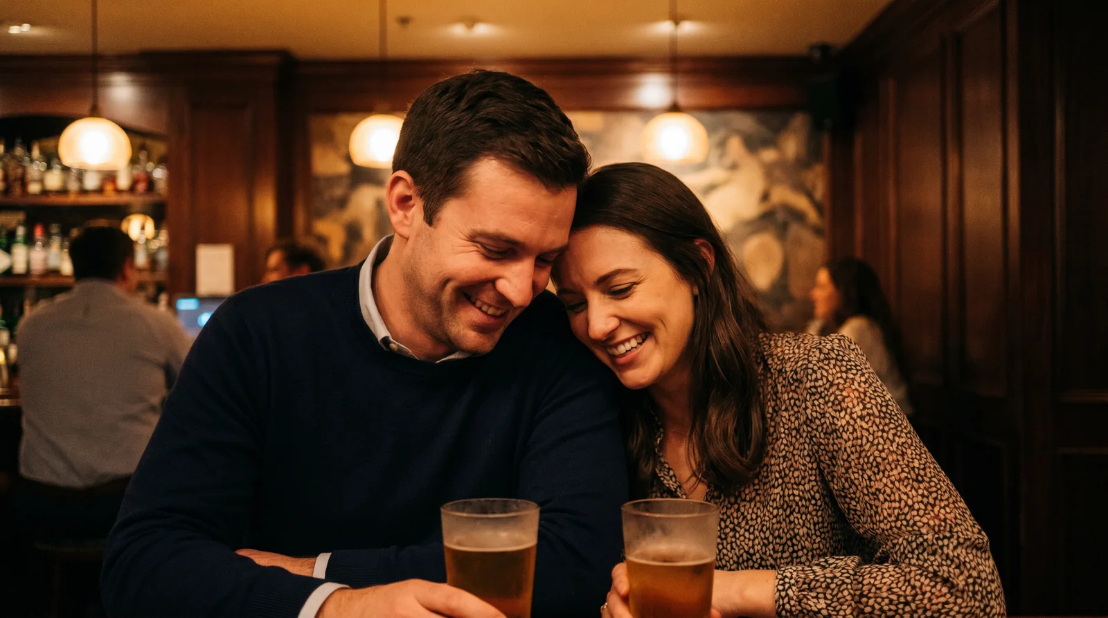 Man and woman laughing together over cocktails at a dimly lit Phoenix cocktail bar